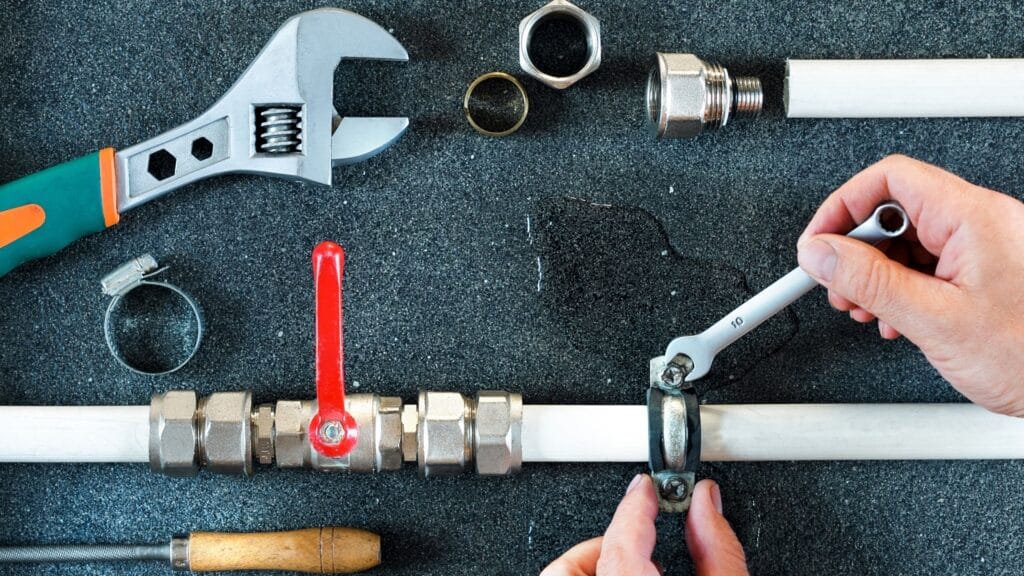 Plumber repairing a pipe valve with an adjustable wrench in Bartow