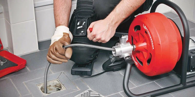 Plumber using a drain-cleaning machine in Bartow