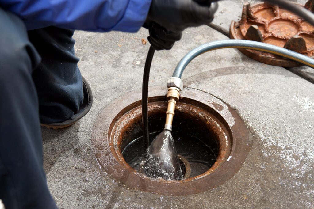 Plumber hydro jetting a sewer line through a manhole in Bartow