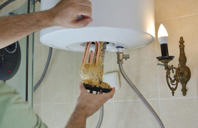 Technician removing mineral buildup from a water heater in Bartow